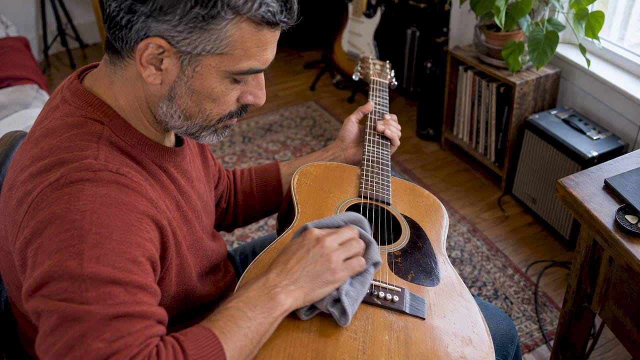 Un guitariste passe un chiffon sur les cordes après avoir joué
